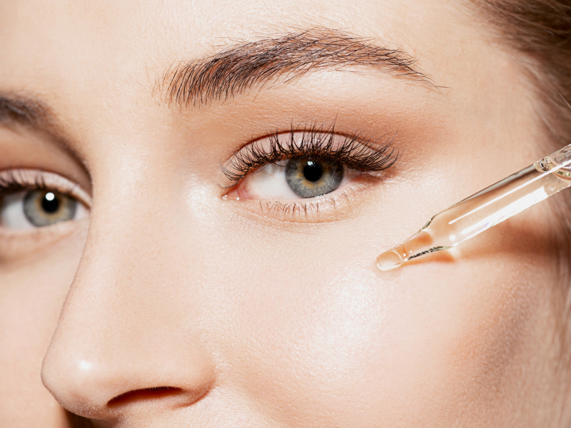 Woman applies a serum on the skin under the eyes