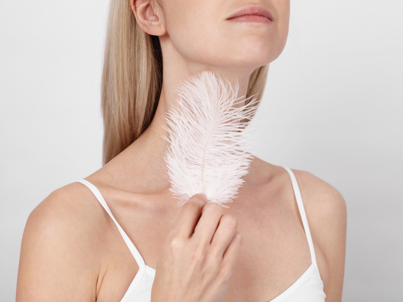 Woman stroking her neck with a feather