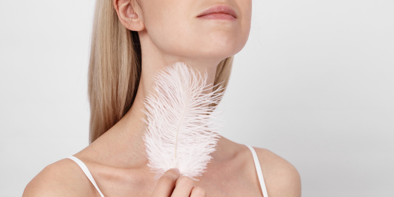 Woman stroking her neck with feather