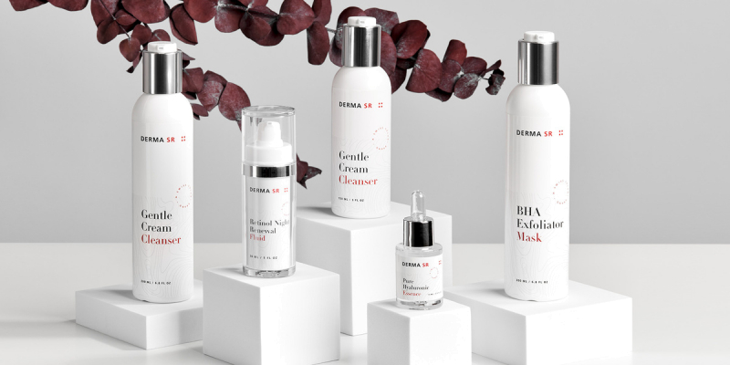 Various facial care products stand on pedestals with leaves in the background